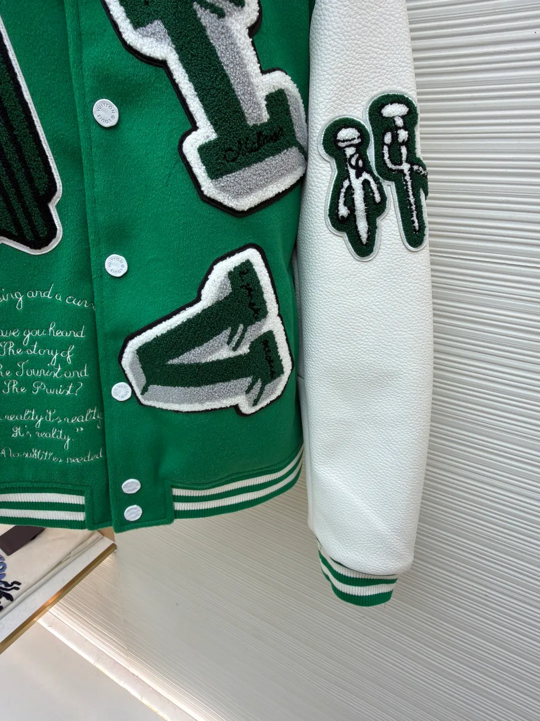 LOUIS VUITTON Loose long-sleeved baseball jersey with monogram pattern ●Original version: Purchased and developed for 29999 ●Item number: 1682254-C10 ●Fabric: cotton fabric ●Technology: embroidery production ●Color: green ●Version: fitted version ●Weight: about 1145 grams ●Size: 46-48-50-52 ●Description: The main body of this Louis Vuitton baseball jacket is made of high-count wool blended fabric. It has been processed by raising and carding processes. The fabric has a full velvety feel and is crisp and stylish. The green base color is made of worsted dyeing process. The color is pure and not easy to fade. The sleeves are spliced ​​with custom pebbled artificial leather, which has been embossed and softened. The texture is natural, flexible to the touch, and is scratch-resistant and wear-resistant. The letters and patterns decorated on the body are made of terry embroidery + appliqué embroidery composite technology. The terry embroidery coils are fluffy and three-dimensional, and the edges of the appliqué embroidery are overlocked to ensure accurate pattern splicing. The handwritten text is made using flat embroidery technology, with fine stitches and clear fonts. The placket is made of custom-made mother-of-pearl buttons, which are hand-polished and polished to have a warm luster; the ribbed neckline and hem are made of spandex blended material, which has good resilience and is not easy to loosen. The overall design uses three-dimensional tailoring and hand-sewing techniques to integrate a variety of materials and embroidery techniques to fully demonstrate the essence of haute couture garments. The overall wiring is straight and delicate, the fabric is comfortable and soft, and the color is consistent without color difference. It can be matched with the same style to create a fashionable look and control various occasions. Customized accessories, complete with three standards, same style for men and women!